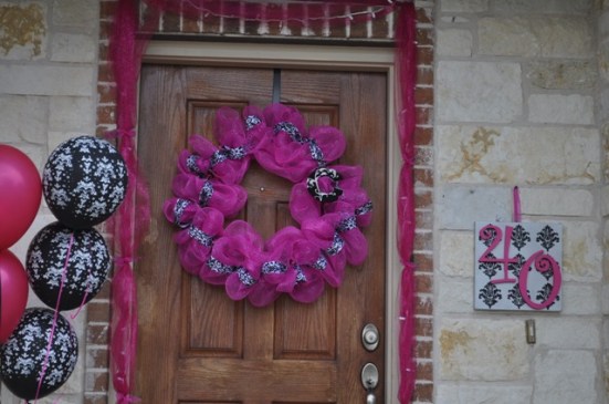 Hot pink tulle with lights, a hot pink wreath on the door, and a painted canvas "40" welcomed guests.